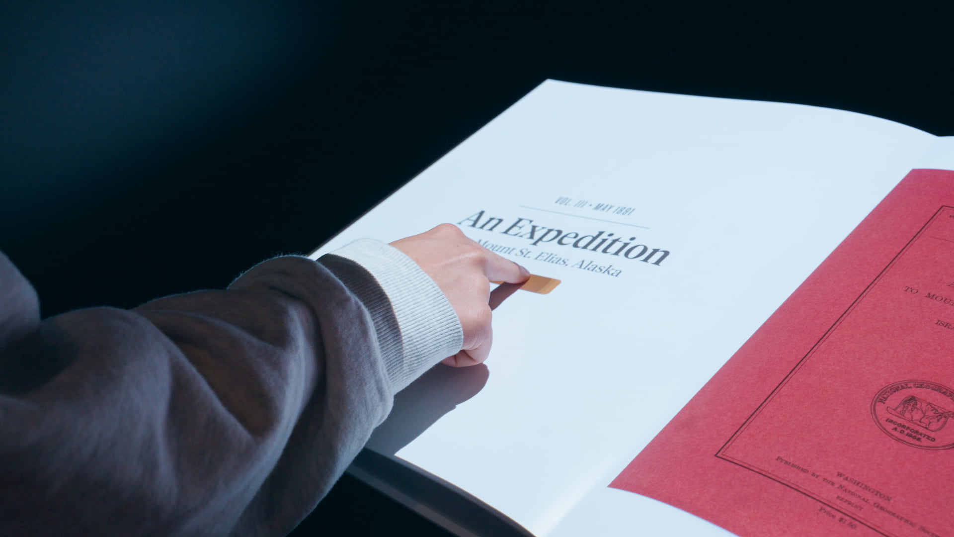 Visitor swiping across a projected magazine page on a sculptural book form